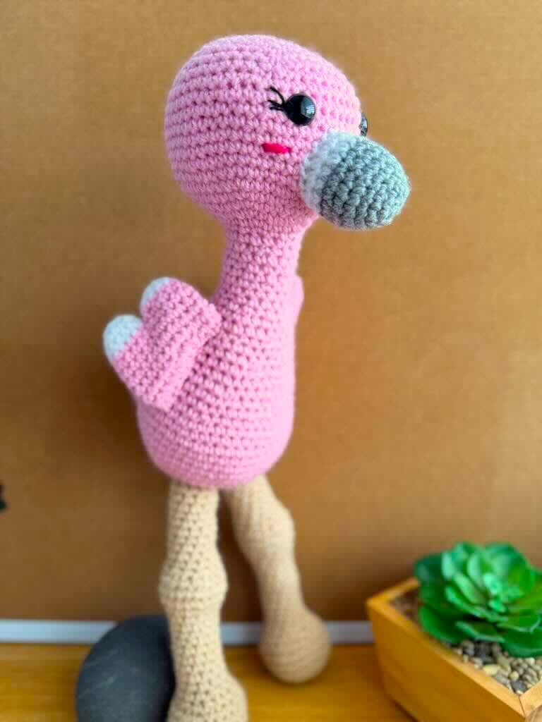 handmade crochet tall pink flamingo with rosy cheeks, long legs, and fluffy wings