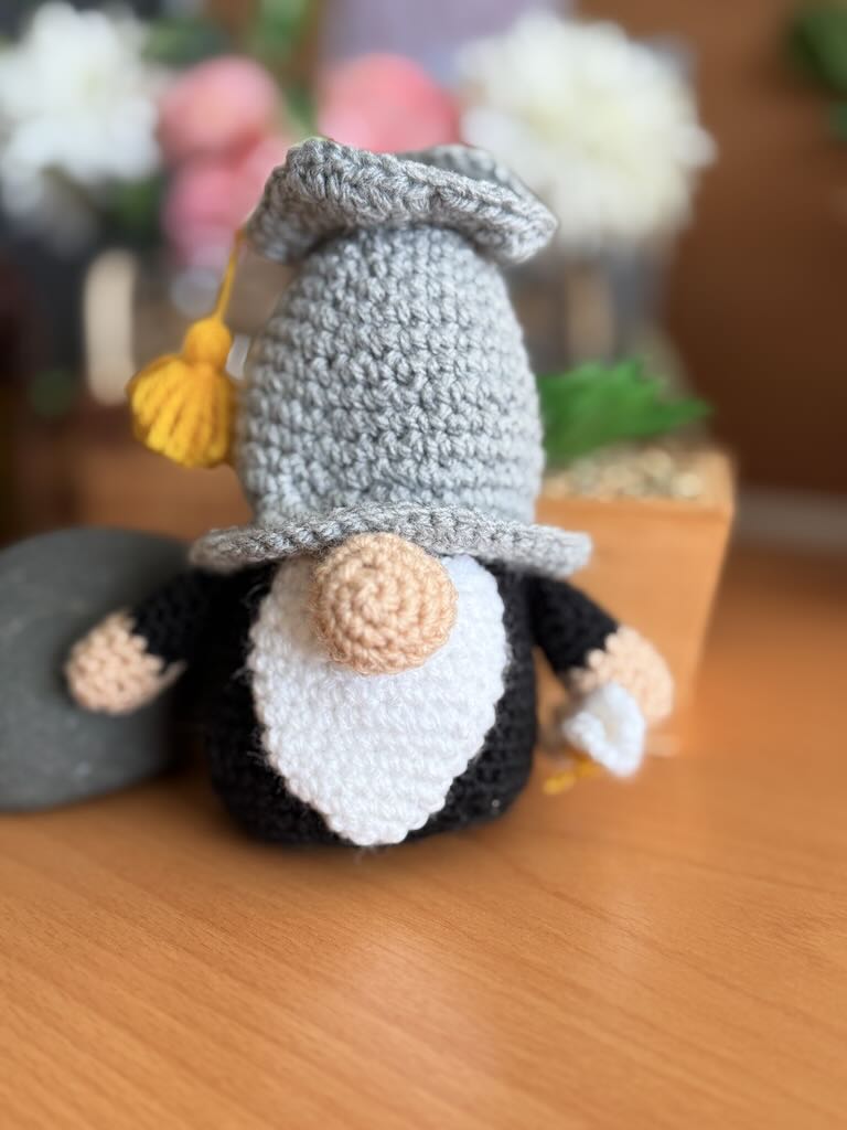 crochet gnome wearing graduation cap and gown, holding diploma