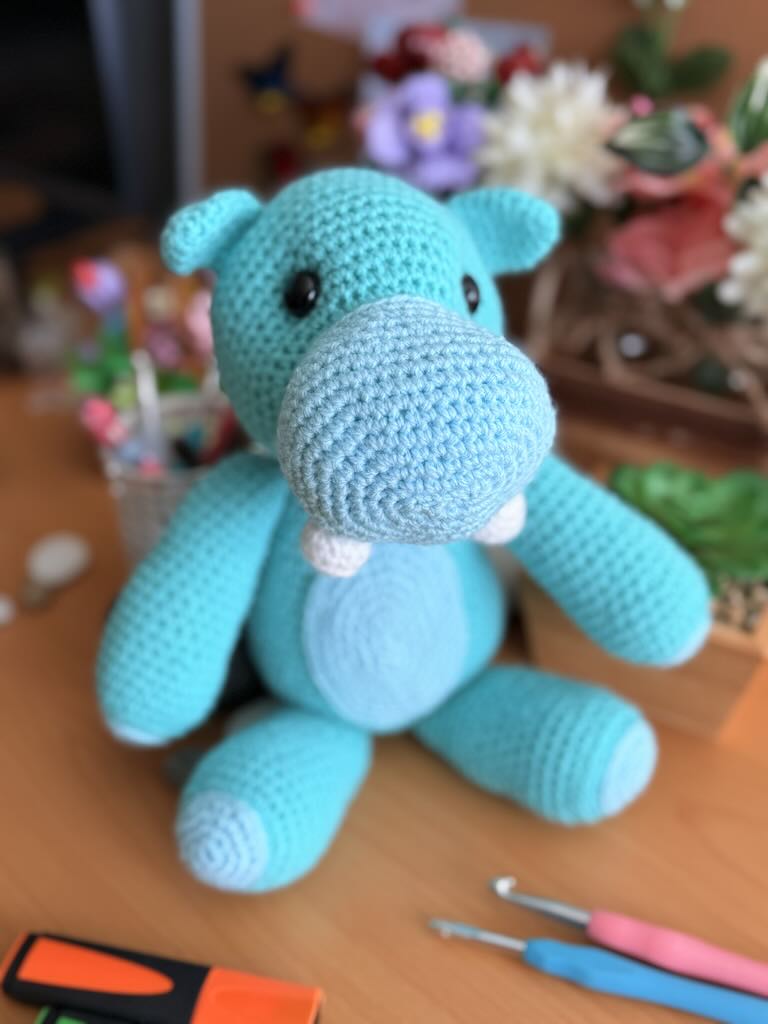 handmade crochet light blue hippo toy named Barry with round body and cheerful expression