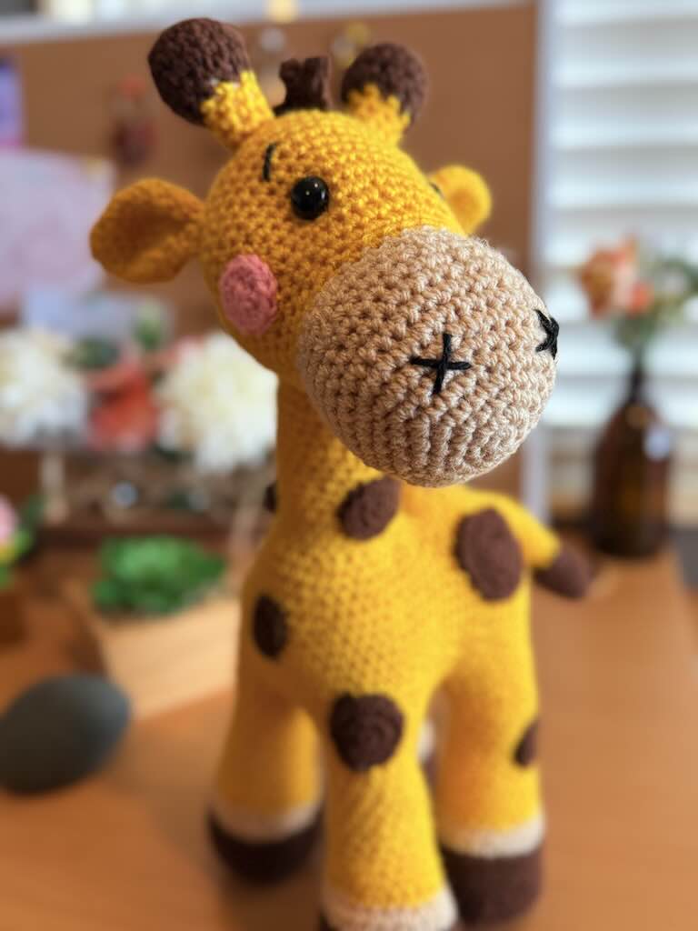 handmade crochet giraffe toy named Gerry with pink cheeks and brown spots