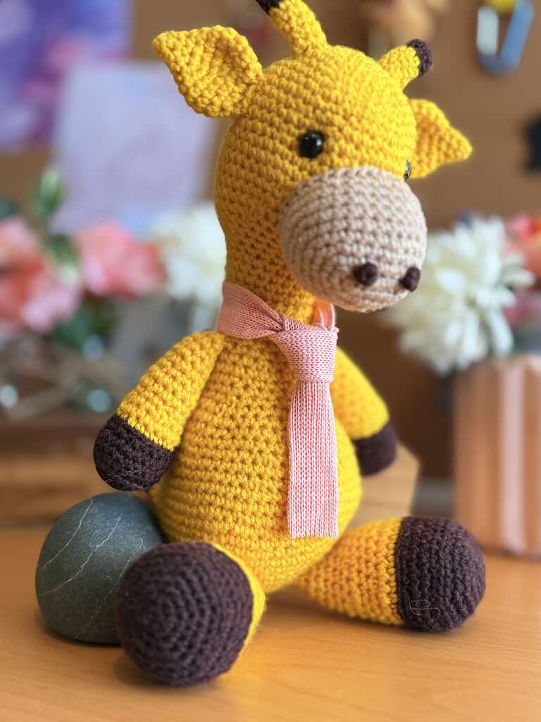 handmade crochet giraffe toy named Terry with tall neck and a pink tie
