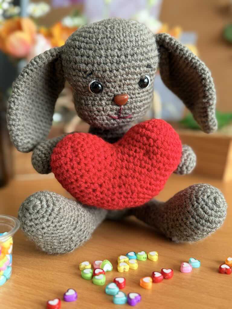 handmade crochet bunny toy with long ears and holding a red heart